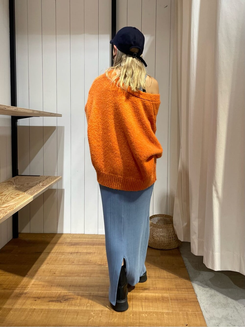 オレンジ系のカーディガン/ボレロ、ブラック系のブーツ、ブルー系のワンピースを着用したレディースの秋コーディネートの6枚目の写真