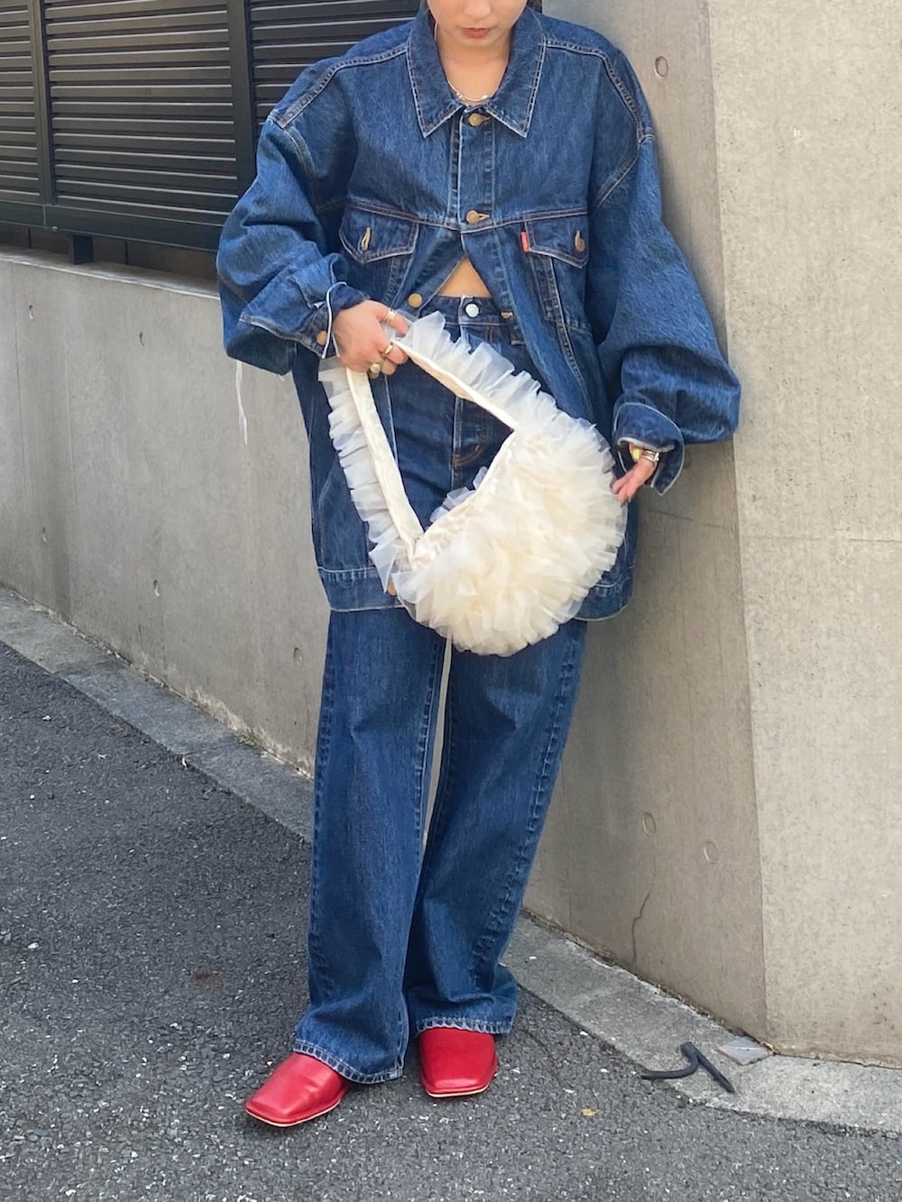 ブルー系のデニムジャケット、ブルー系のデニムパンツ、ホワイト系のショルダーバッグを着用したレディースの夏コーディネートの2枚目の写真