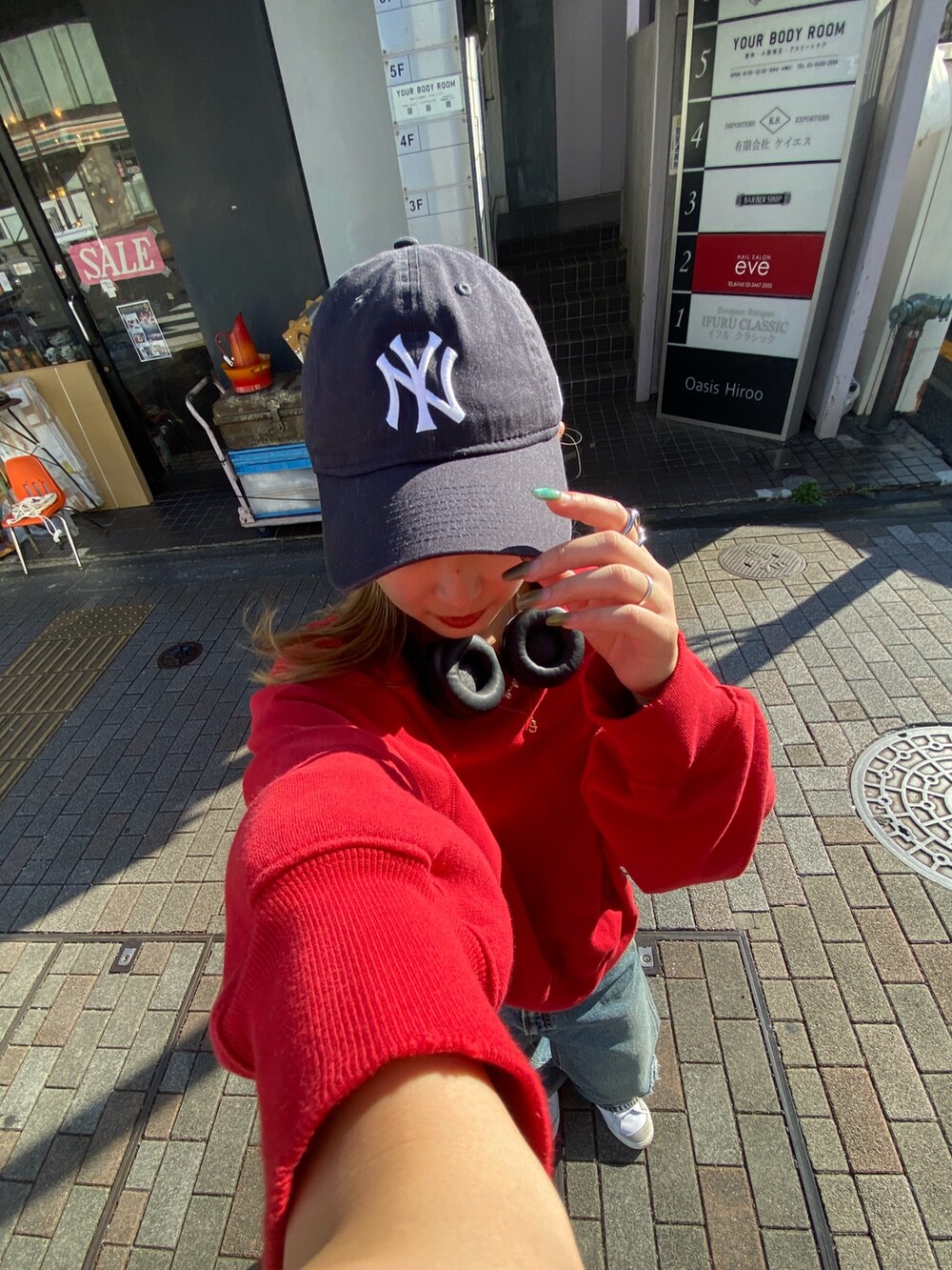 レッド系のニット/セーター、ブルー系のデニムパンツを着用したレディースの秋コーディネートの3枚目の写真