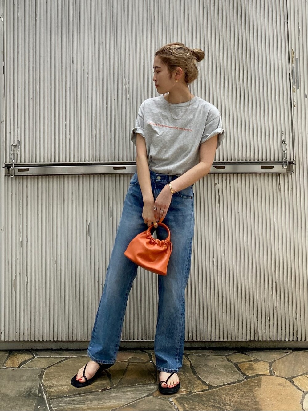 ブルー系のデニムパンツ、ブラック系のサンダル、グレー系のTシャツ/カットソーを着用したレディースの夏コーディネートの2枚目の写真