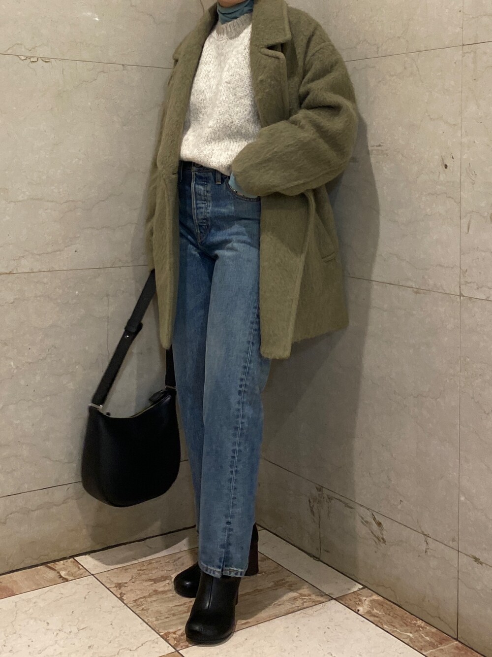 ホワイト系のニット/セーター、ブルー系のTシャツ/カットソー、グリーン系のピーコートを着用したレディースの冬コーディネートの4枚目の写真