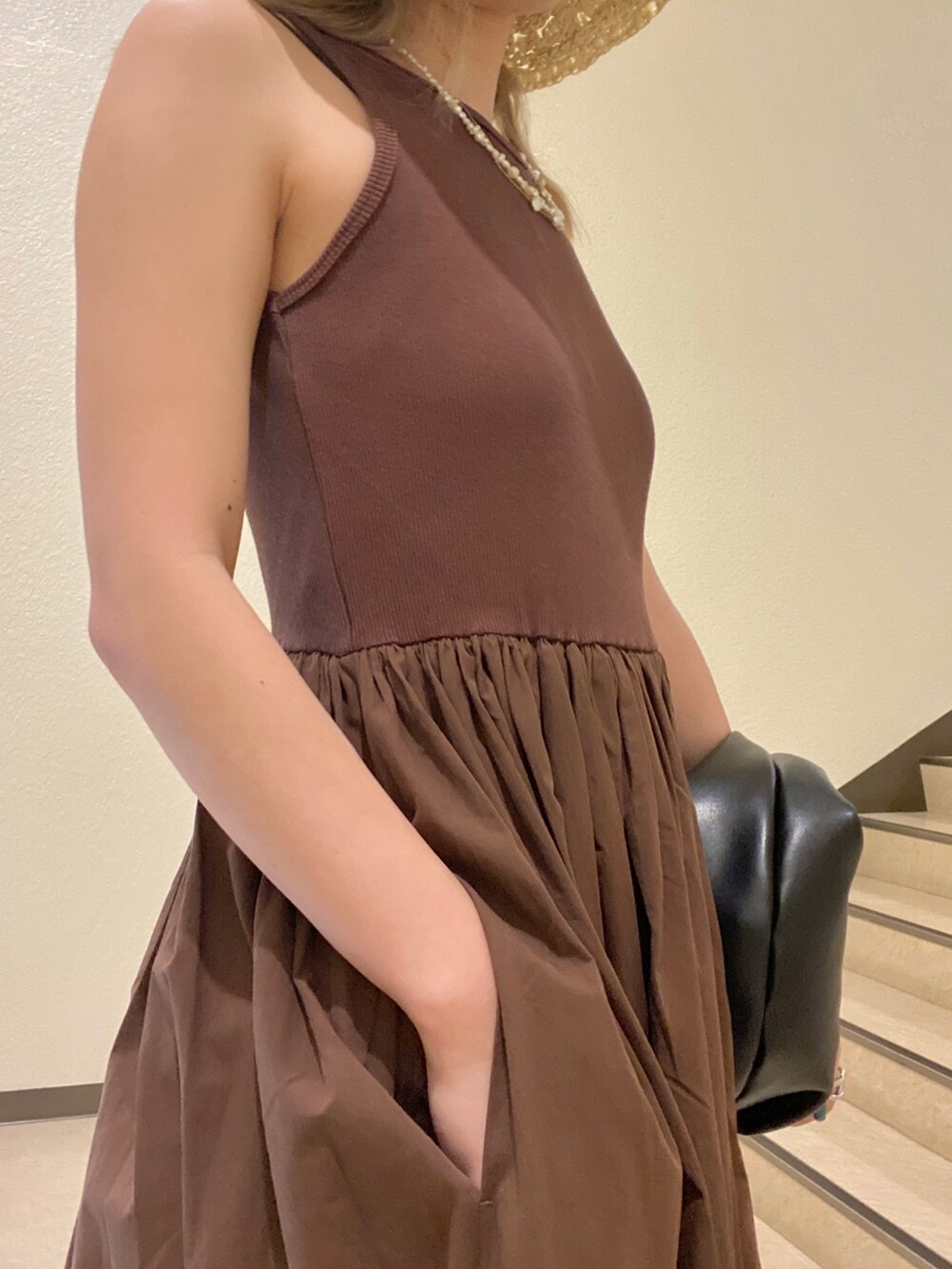 ブラック系のハンドバッグ、ブラウン系のワンピース、ベージュ系のハットを着用したレディースの夏コーディネートの4枚目の写真