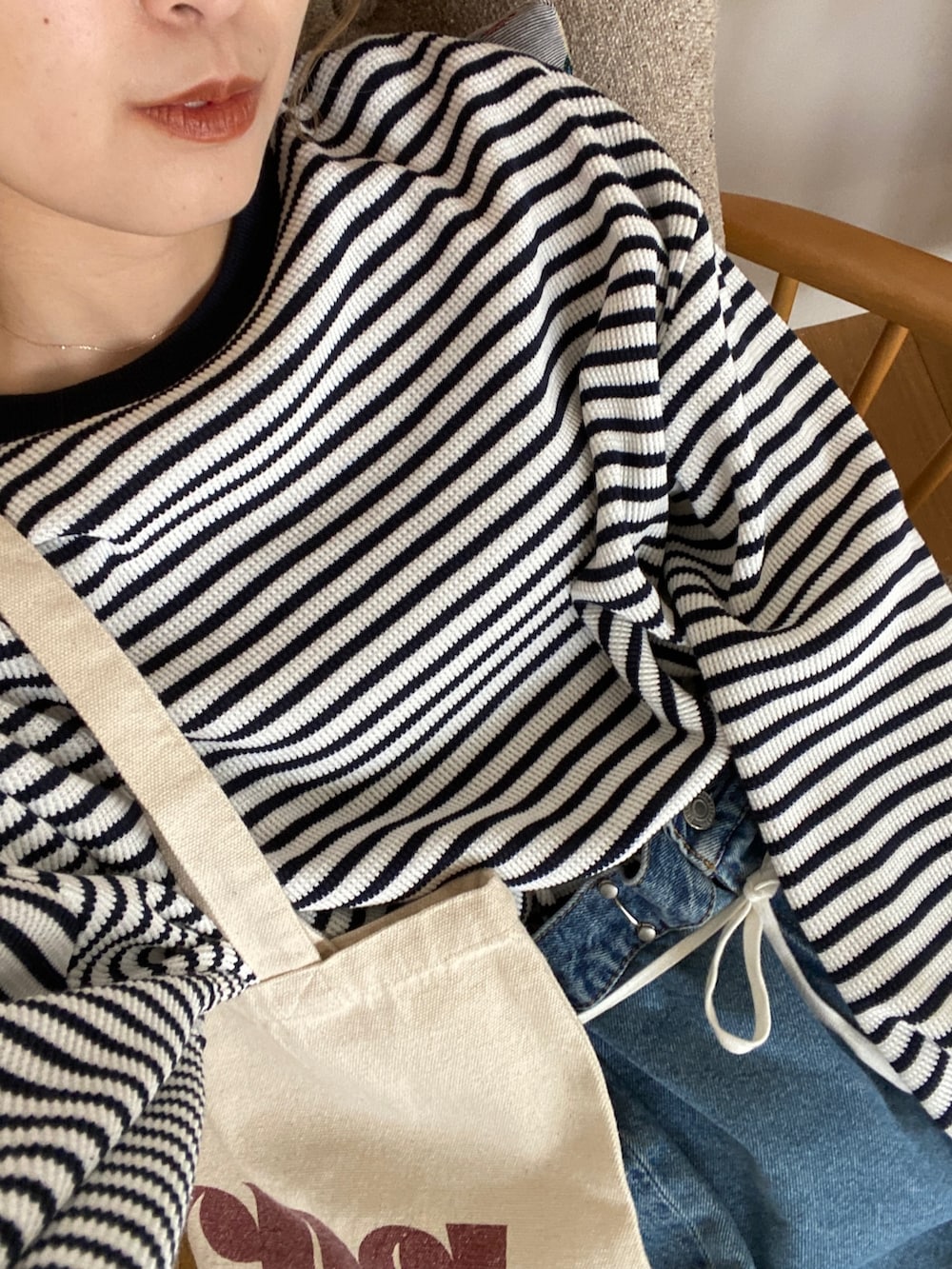 ブルー系のTシャツ/カットソー、ブルー系のデニムパンツ、レッド系のトートバッグを着用したレディースの冬コーディネートの3枚目の写真