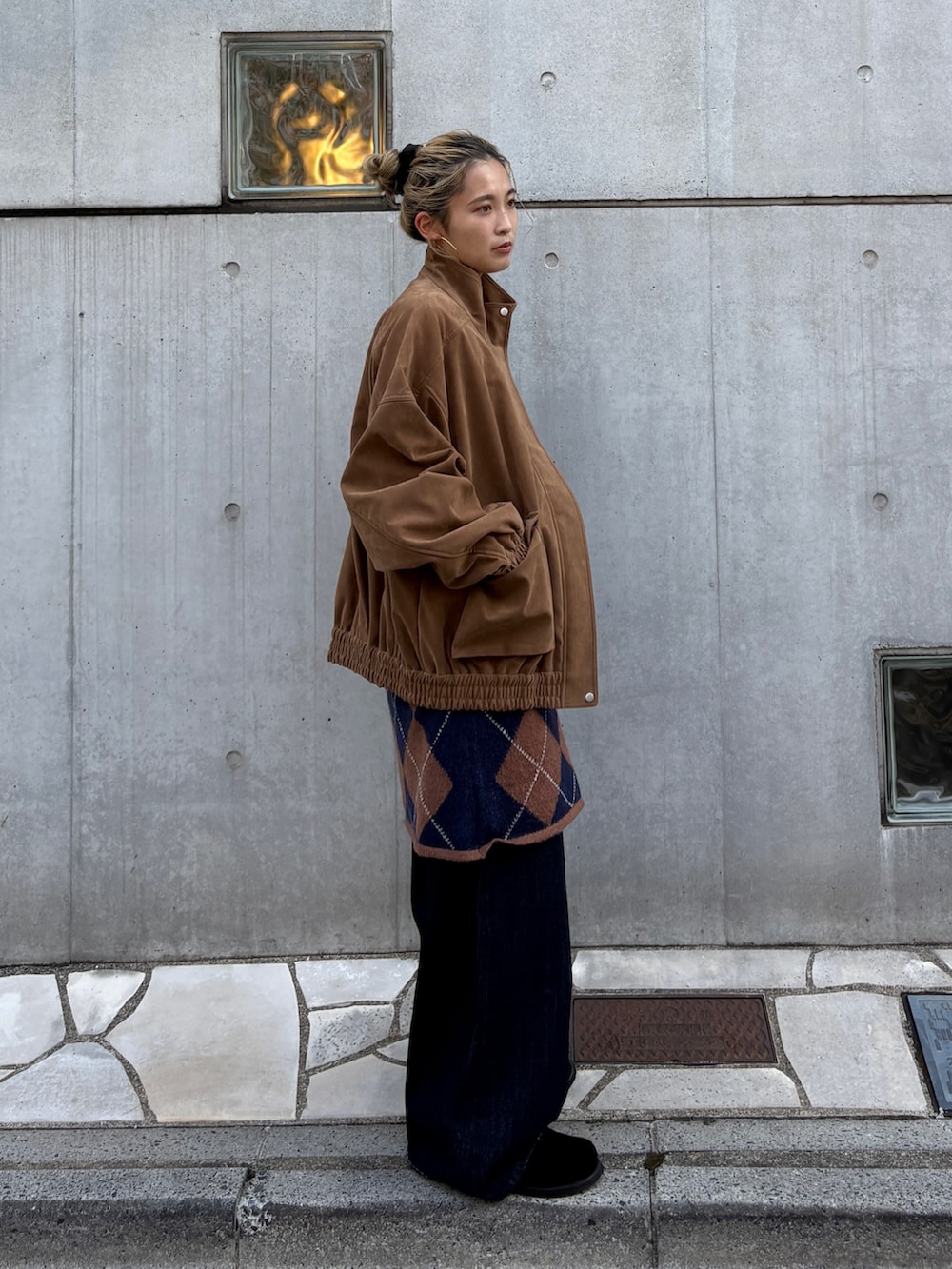ブラウン系のブルゾン、ブラウン系のニット/セーター、ブルー系のデニムパンツを着用したレディースの秋コーディネートの3枚目の写真