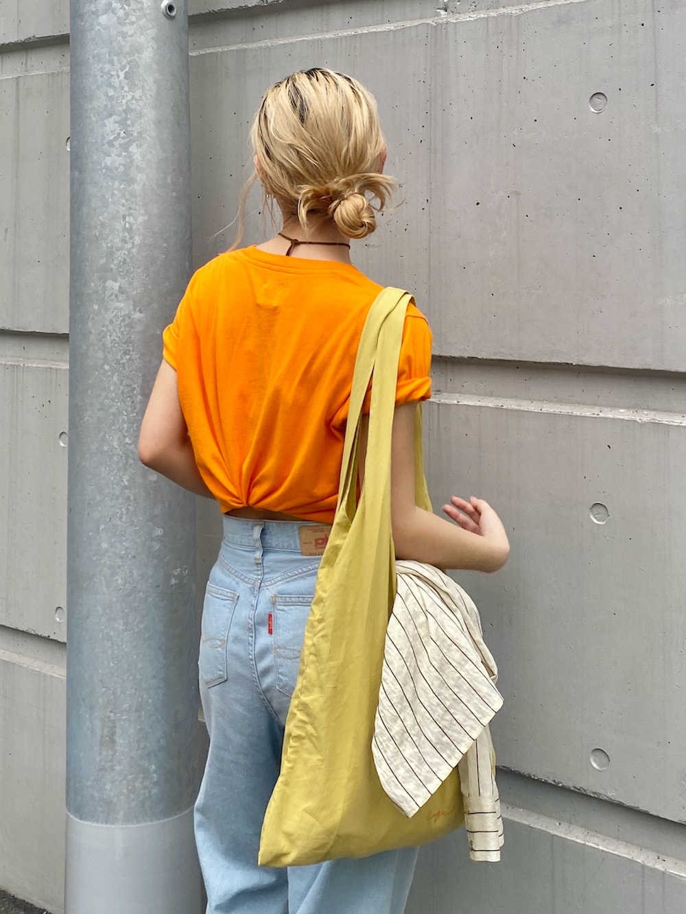 オレンジ系のTシャツ/カットソー、ブルー系のデニムパンツ、その他のサンダルを着用したレディースの春コーディネートの4枚目の写真