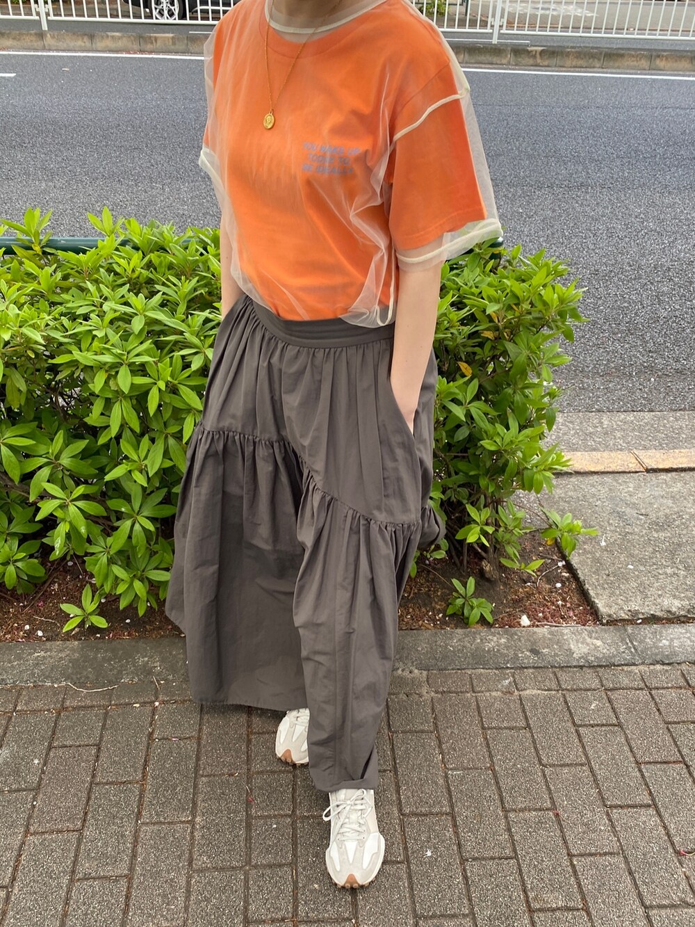 オレンジ系のTシャツ/カットソー、グレー系のスカートを着用したレディースの春コーディネートの3枚目の写真