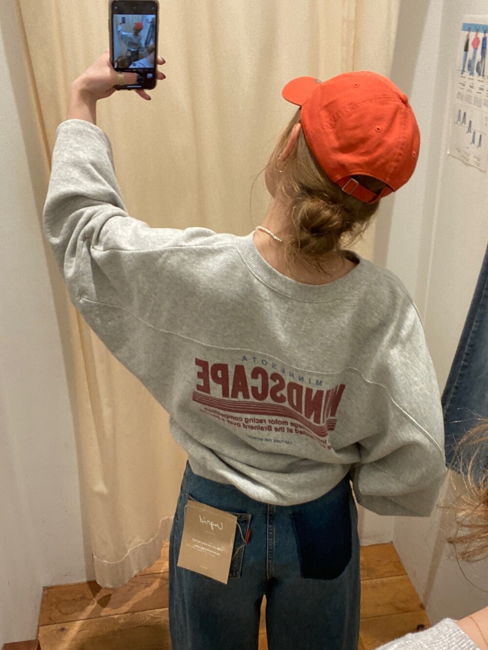 グレー系のスウェット、ブルー系のデニムパンツ、オレンジ系のキャップを着用したレディースの春コーディネートの3枚目の写真