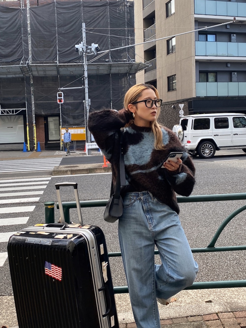 ブラウン系のニット/セーター、ブルー系のデニムパンツ、ブラック系のメガネを着用したレディースの秋コーディネートの3枚目の写真