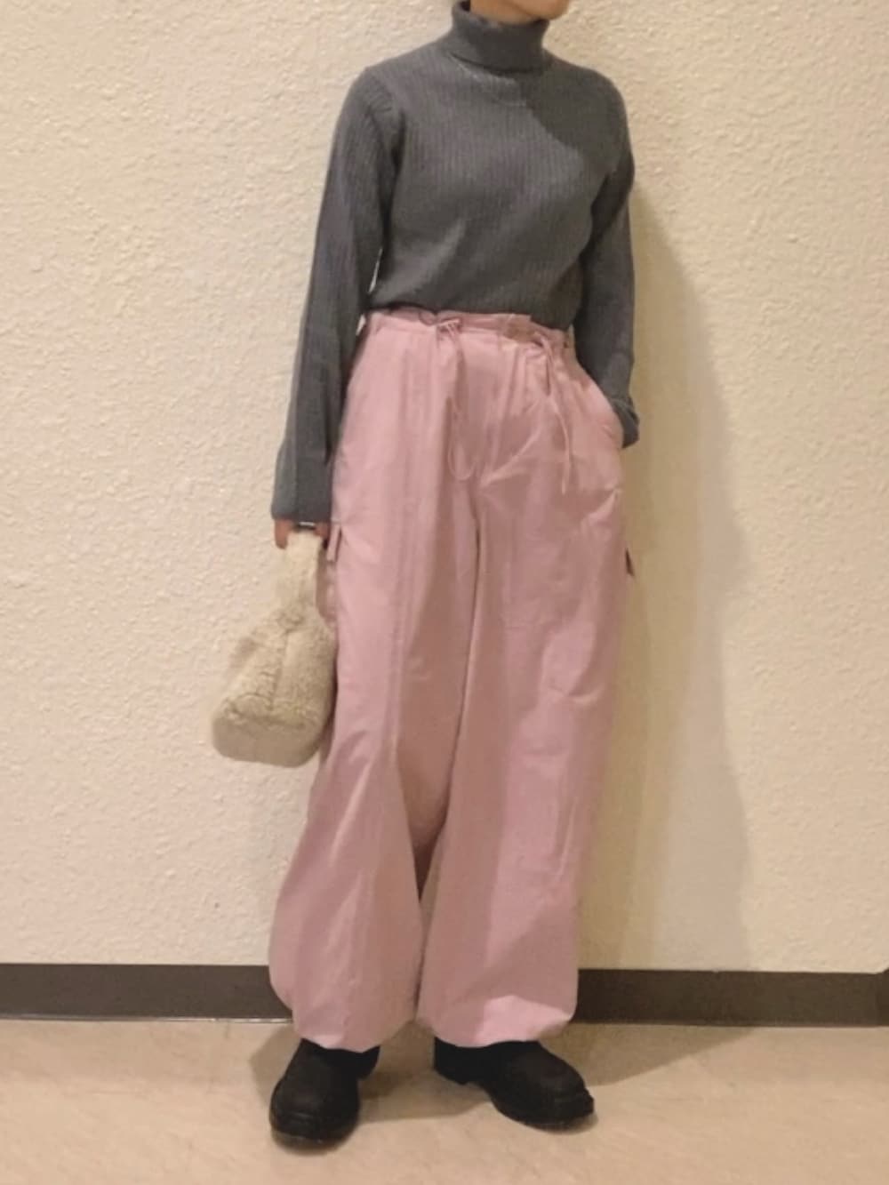 グレー系のニット/セーター、ピンク系のカーゴパンツ、ホワイト系のハンドバッグを着用したレディースの冬コーディネートの2枚目の写真