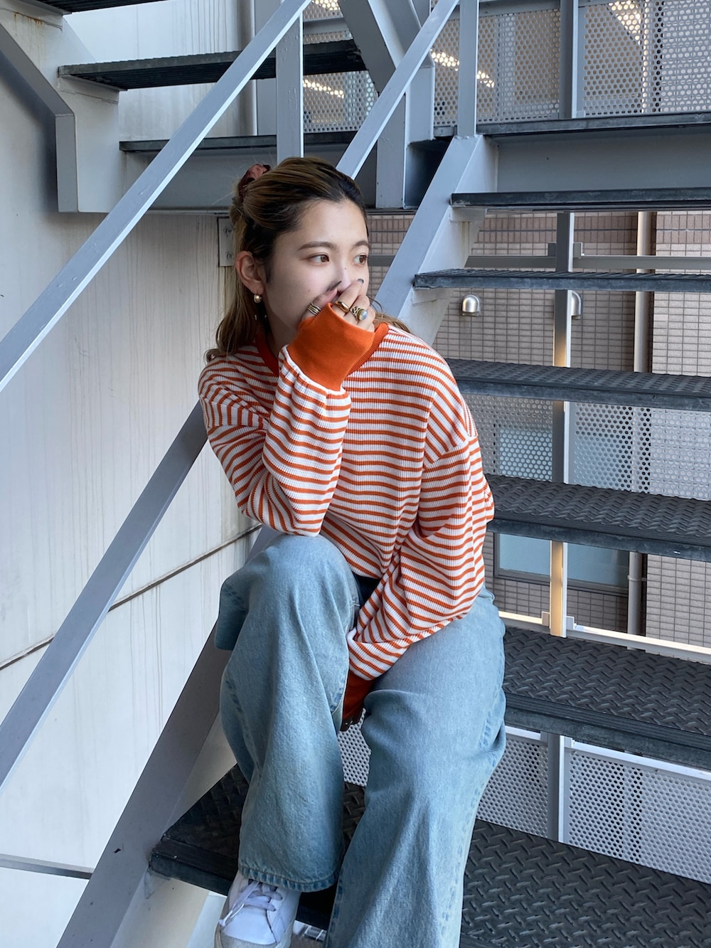 オレンジ系のTシャツ/カットソー、ブルー系のデニムパンツを着用したレディースの冬コーディネートの3枚目の写真