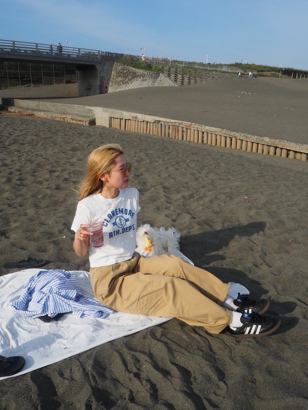 ホワイト系のTシャツ/カットソー、ベージュ系のチノパンツ、ホワイト系のショルダーバッグを着用したレディースの春コーディネートの2枚目の写真