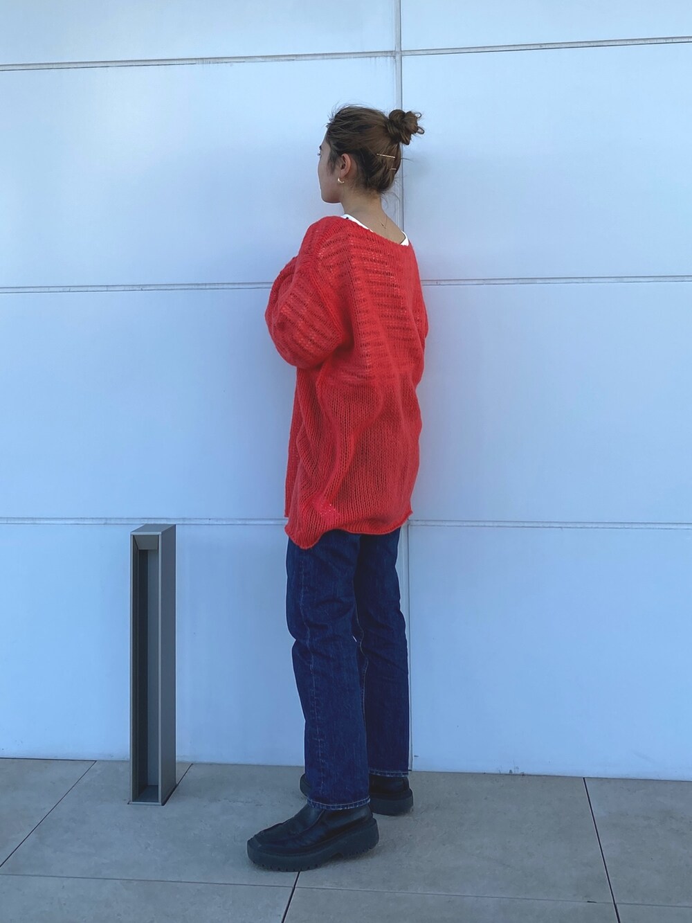 オレンジ系のニット/セーター、ブルー系のTシャツ/カットソーを着用したレディースの冬コーディネートの2枚目の写真