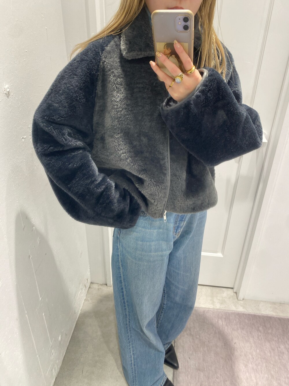 グレー系のブルゾン、ホワイト系のTシャツ/カットソー、ブルー系のデニムパンツを着用したレディースの冬コーディネートの2枚目の写真