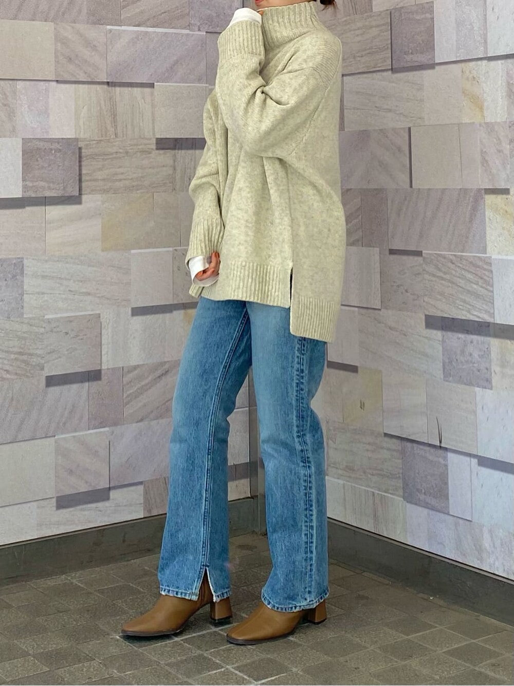 ブルー系のデニムパンツ、ホワイト系のニット/セーター、ホワイト系のTシャツ/カットソーを着用したレディースの冬コーディネートの2枚目の写真