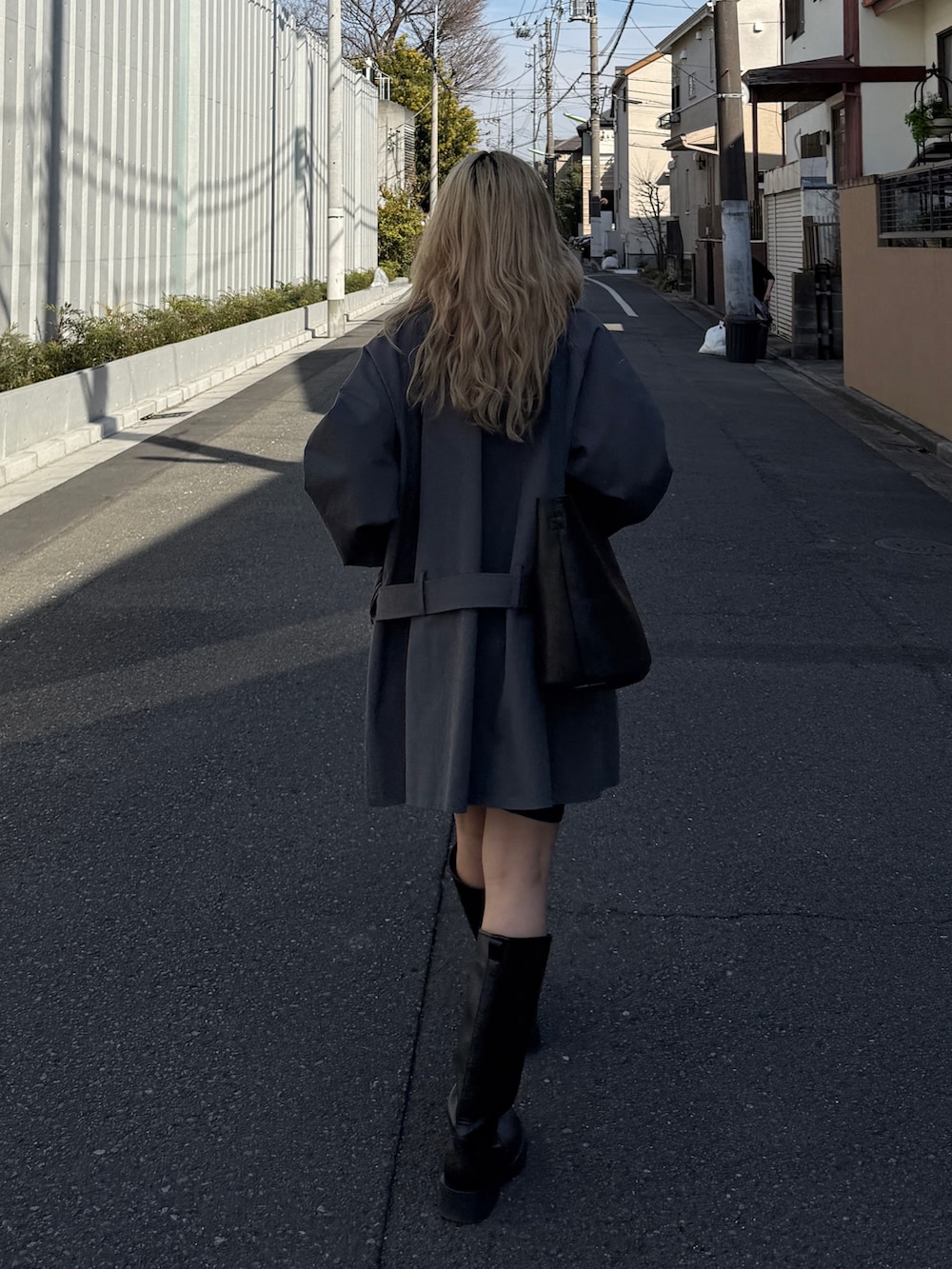 グレー系のトレンチコート、ブラック系のブーツを着用したレディースの冬コーディネートの3枚目の写真