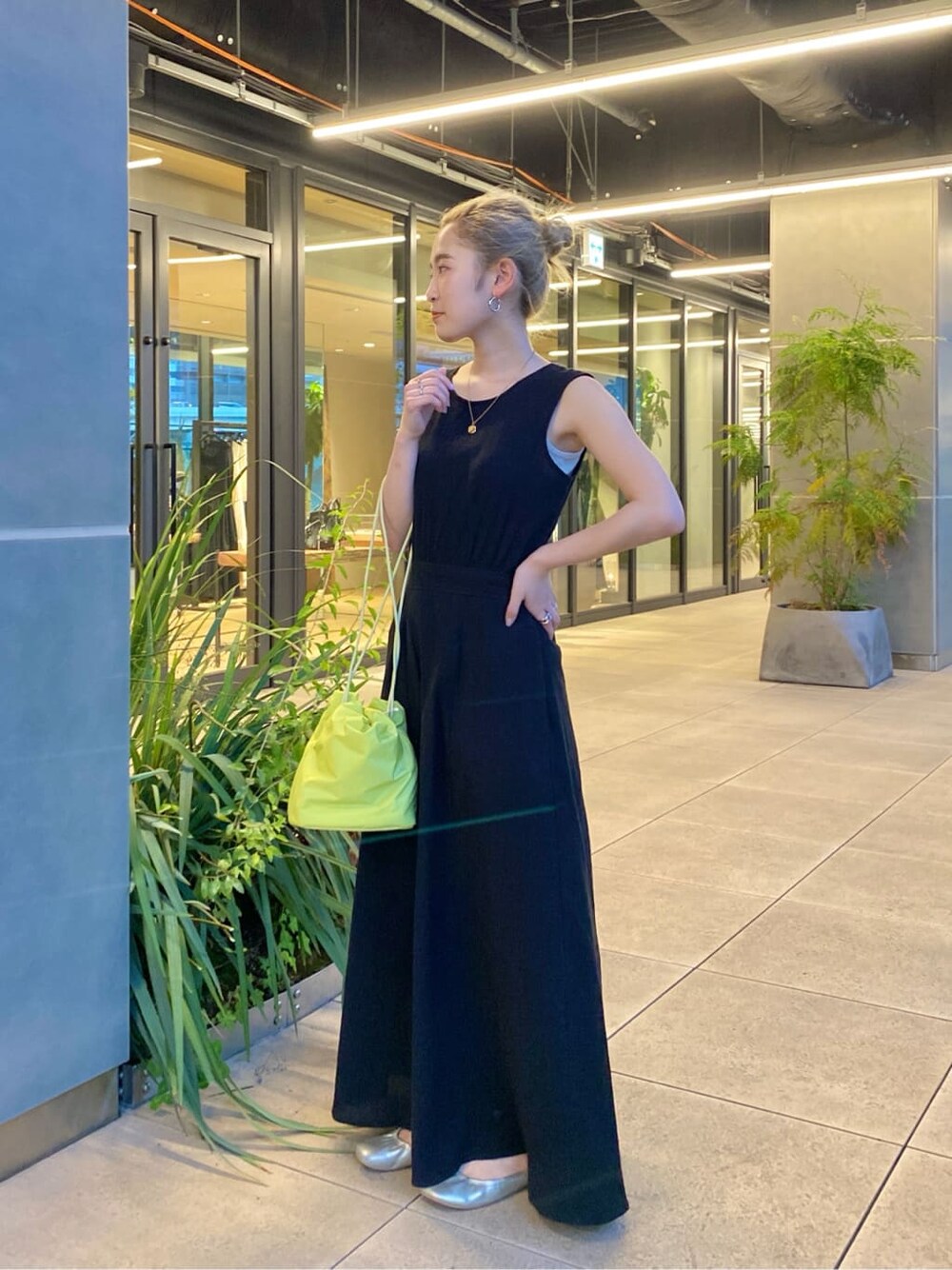 グリーン系のハンドバッグ、ブラック系のワンピースを着用したレディースの春コーディネートの2枚目の写真