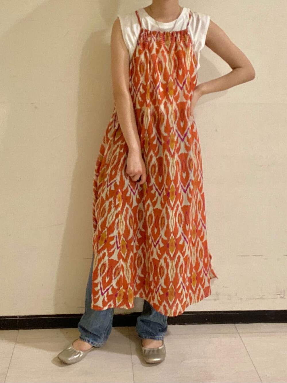 ホワイト系のタンクトップ、オレンジ系のワンピース、ブルー系のデニムパンツを着用したレディースの春コーディネートの2枚目の写真