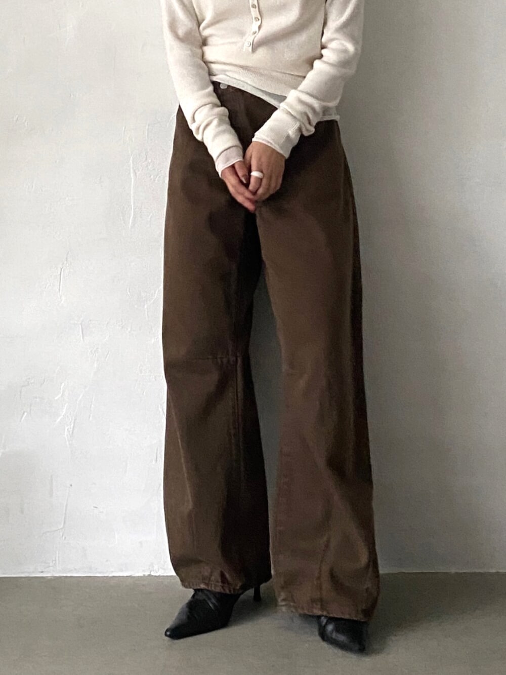 ブラック系のパンプス、ブラウン系のデニムパンツ、ホワイト系のニット/セーターを着用したレディースの秋コーディネートの4枚目の写真