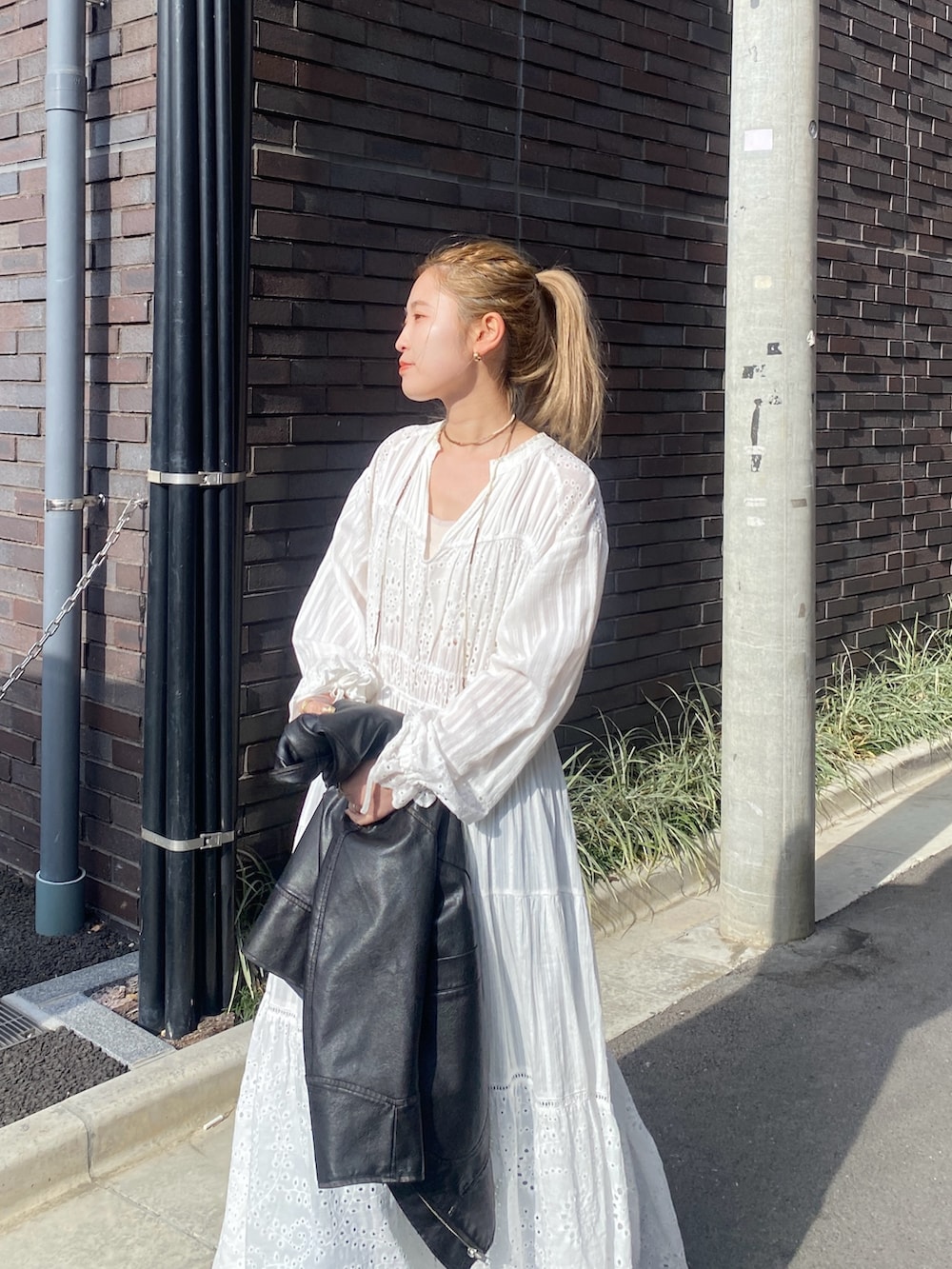 ブラック系のブルゾン、ホワイト系のワンピース、ブルー系のデニムパンツを着用したレディースの冬コーディネートの4枚目の写真