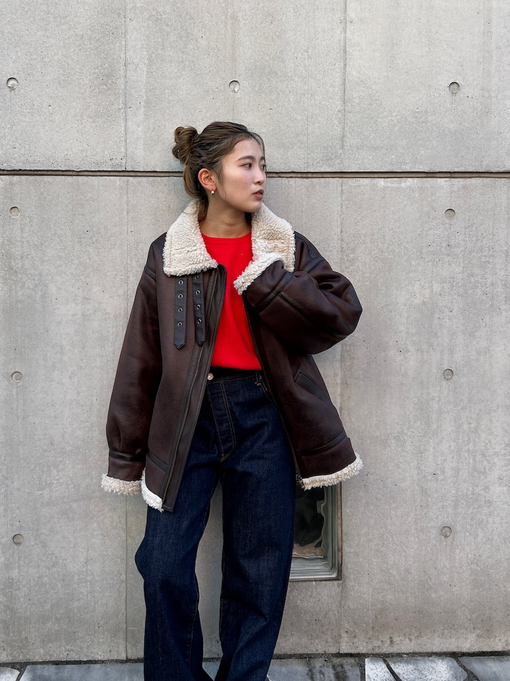 レッド系のニット/セーター、ブラウン系のブルゾン、ブルー系のデニムパンツを着用したレディースの冬コーディネートの3枚目の写真
