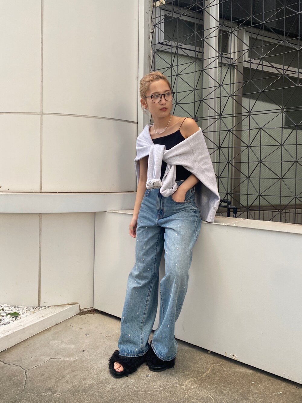 グレー系のスウェット、ブルー系のデニムパンツ、ブラック系のサンダルを着用したレディースの秋コーディネートの3枚目の写真