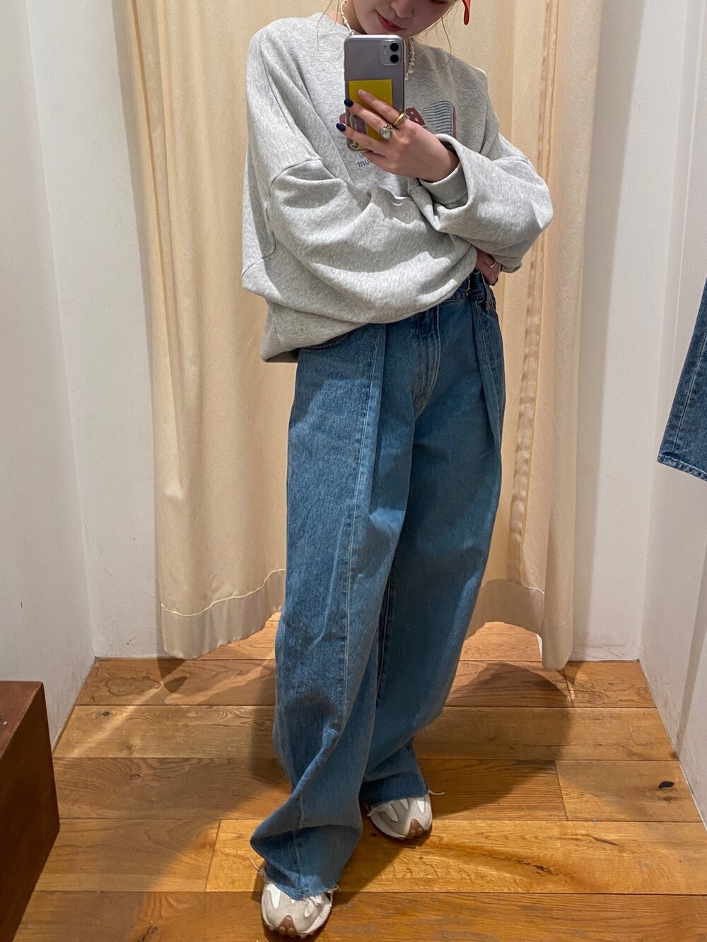 グレー系のスウェット、ブルー系のデニムパンツ、オレンジ系のキャップを着用したレディースの春コーディネートの4枚目の写真