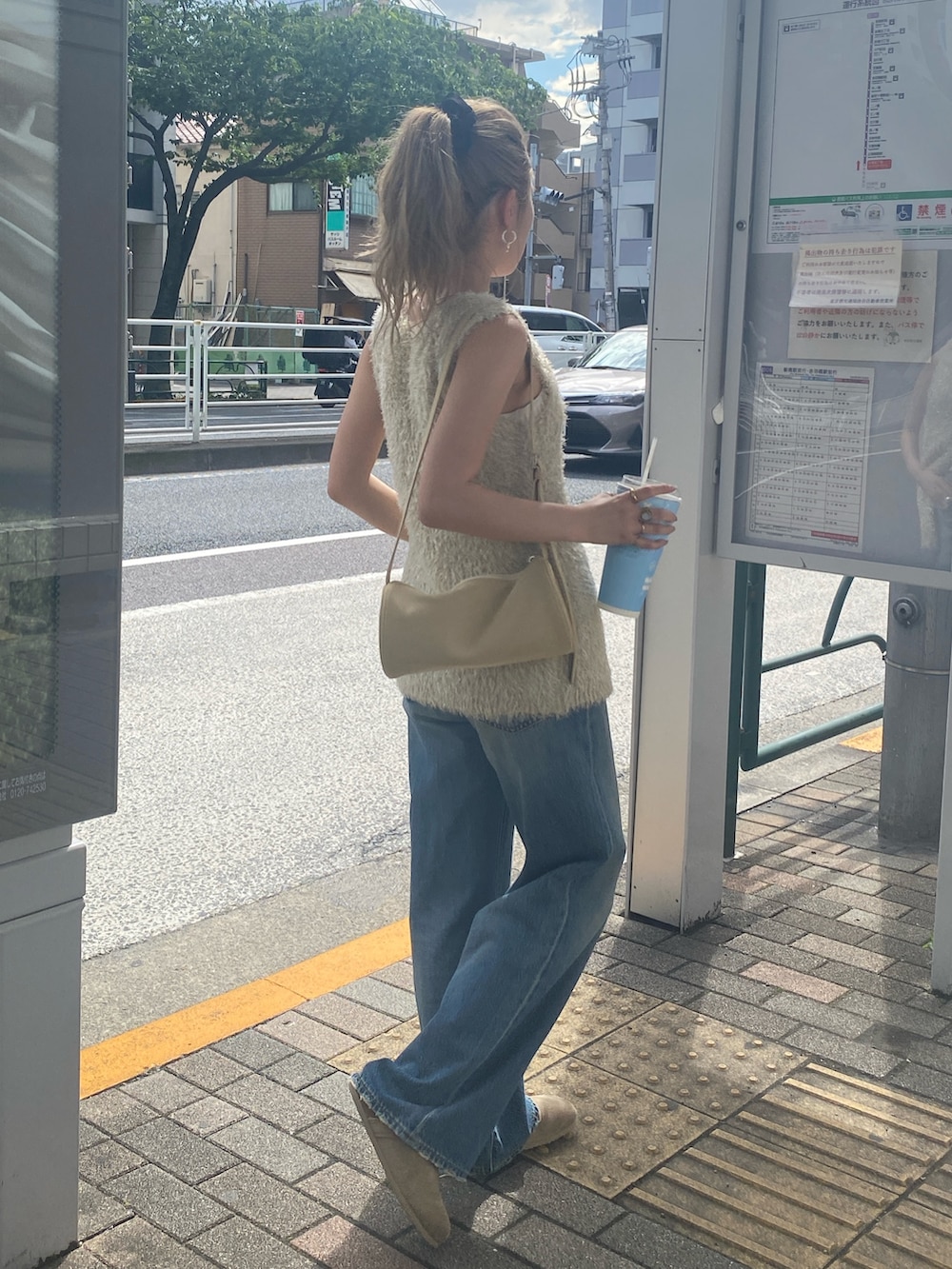 ゴールド系のニット/セーター、ブルー系のデニムパンツを着用したレディースの夏コーディネートの4枚目の写真