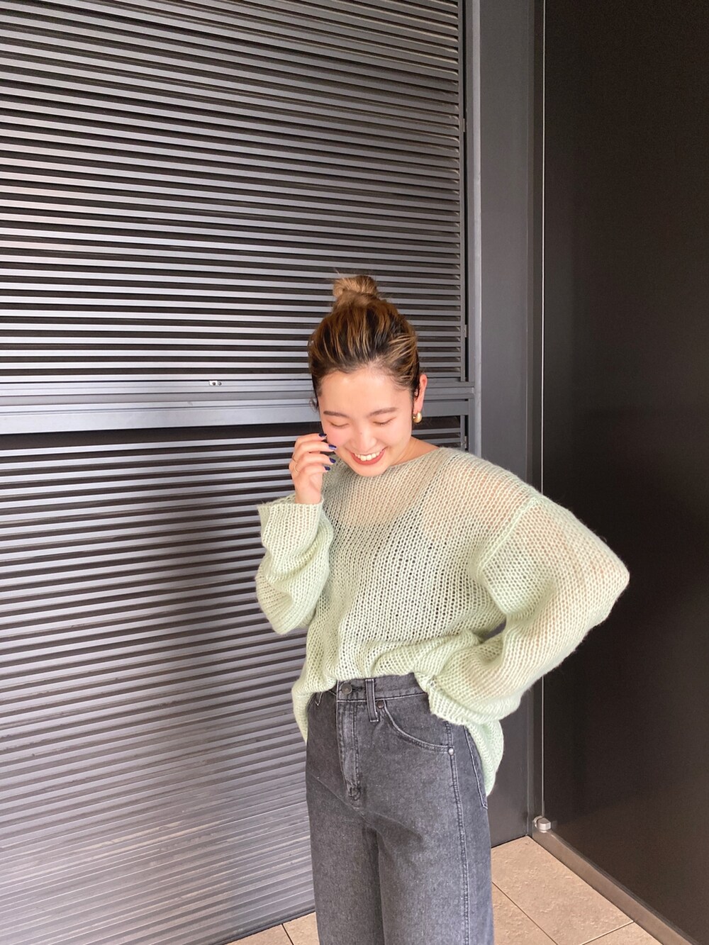 グリーン系のニット/セーター、ブラック系のデニムパンツを着用したレディースの冬コーディネートの6枚目の写真