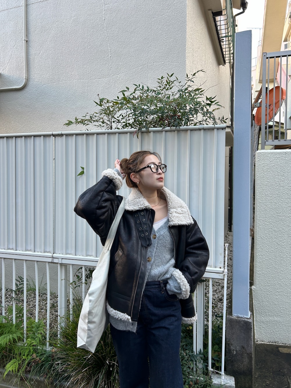 ブラック系のブルゾン、グレー系のカーディガン/ボレロ、ブルー系のデニムパンツを着用したレディースの冬コーディネートの3枚目の写真