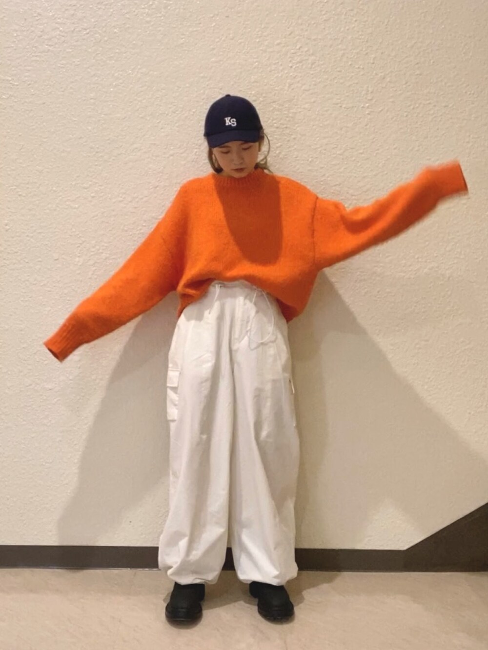 オレンジ系のニット/セーター、ホワイト系のカーゴパンツ、ブラック系のブーツを着用したレディースの冬コーディネートの3枚目の写真