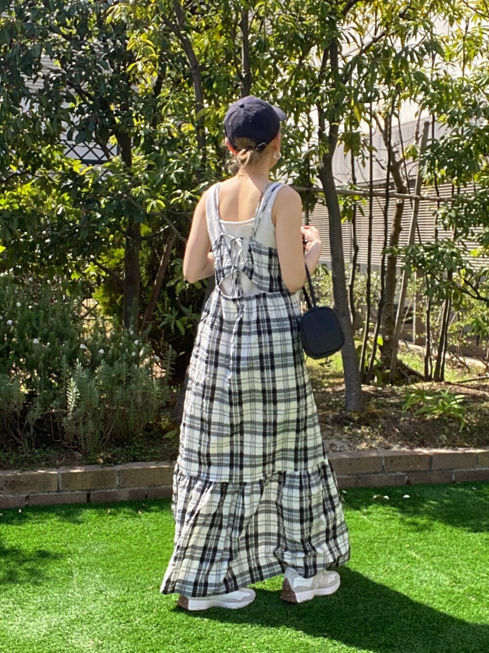 ホワイト系のニット/セーター、ブラック系のワンピース、ブラック系のハンドバッグを着用したレディースの春コーディネートの4枚目の写真