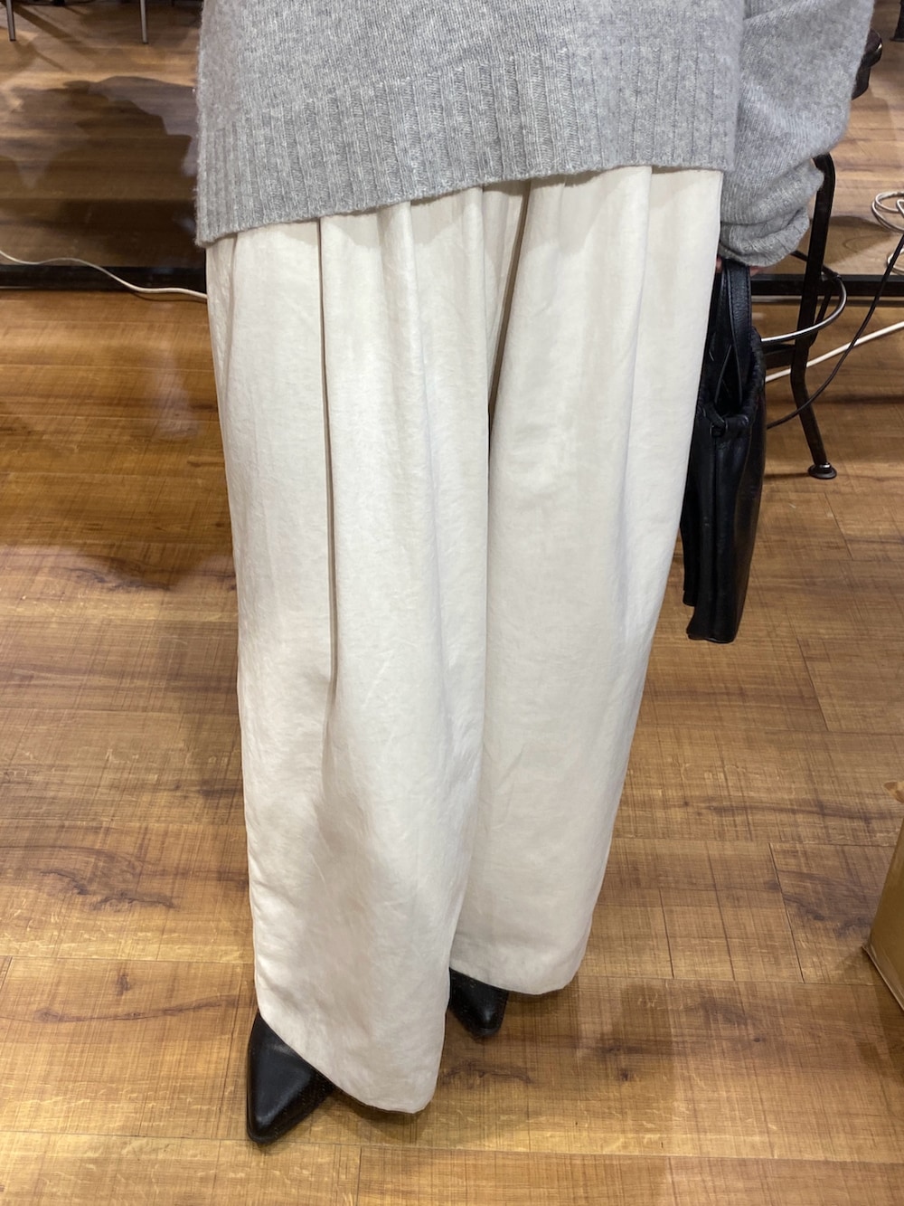 グレー系のニット/セーター、ホワイト系のその他パンツ、ブラック系のショルダーバッグを着用したレディースの秋コーディネートの3枚目の写真