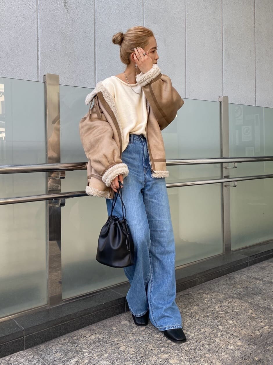 ブルー系のデニムパンツ、ブラック系のブーツ、ブラック系のハンドバッグを着用したレディースの秋コーディネートの2枚目の写真