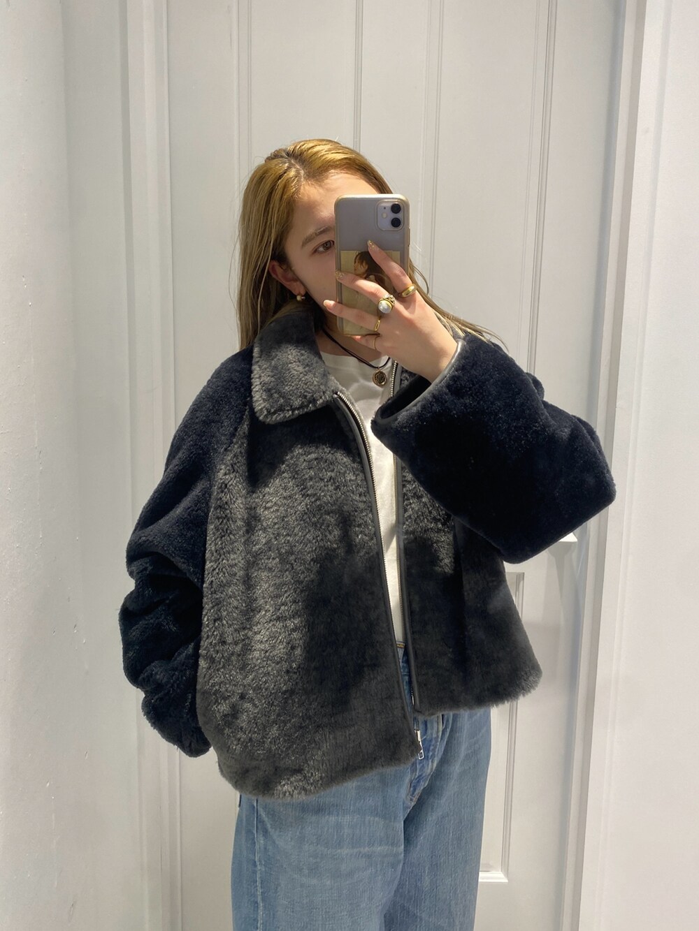 グレー系のブルゾン、ホワイト系のTシャツ/カットソー、ブルー系のデニムパンツを着用したレディースの冬コーディネートの3枚目の写真