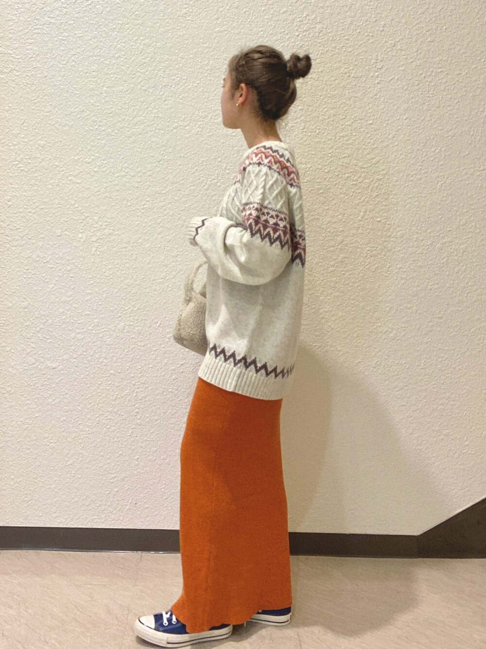 オレンジ系のスカート、ホワイト系のニット/セーター、ホワイト系のハンドバッグを着用したレディースの秋コーディネートの3枚目の写真