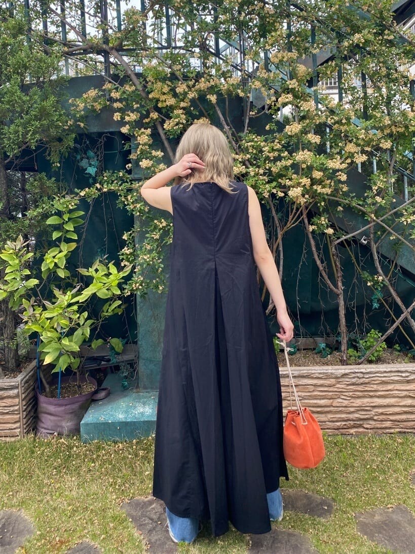 オレンジ系のハンドバッグ、ブルー系のデニムパンツ、ブラック系のワンピースを着用したレディースの春コーディネートの3枚目の写真