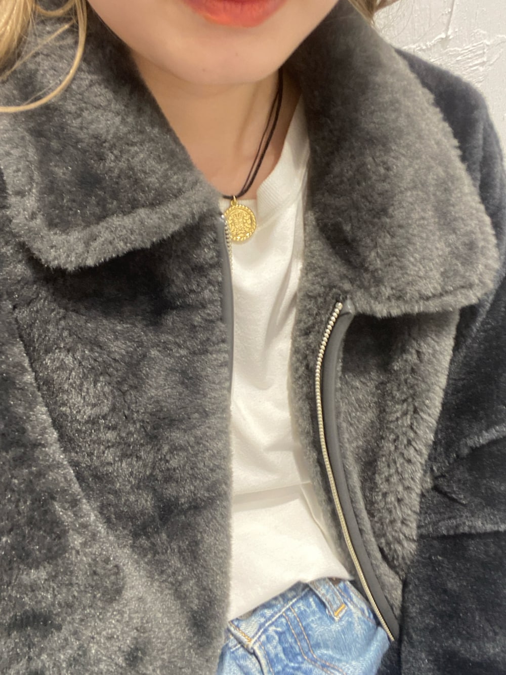 グレー系のブルゾン、ホワイト系のTシャツ/カットソー、ブルー系のデニムパンツを着用したレディースの冬コーディネートの4枚目の写真