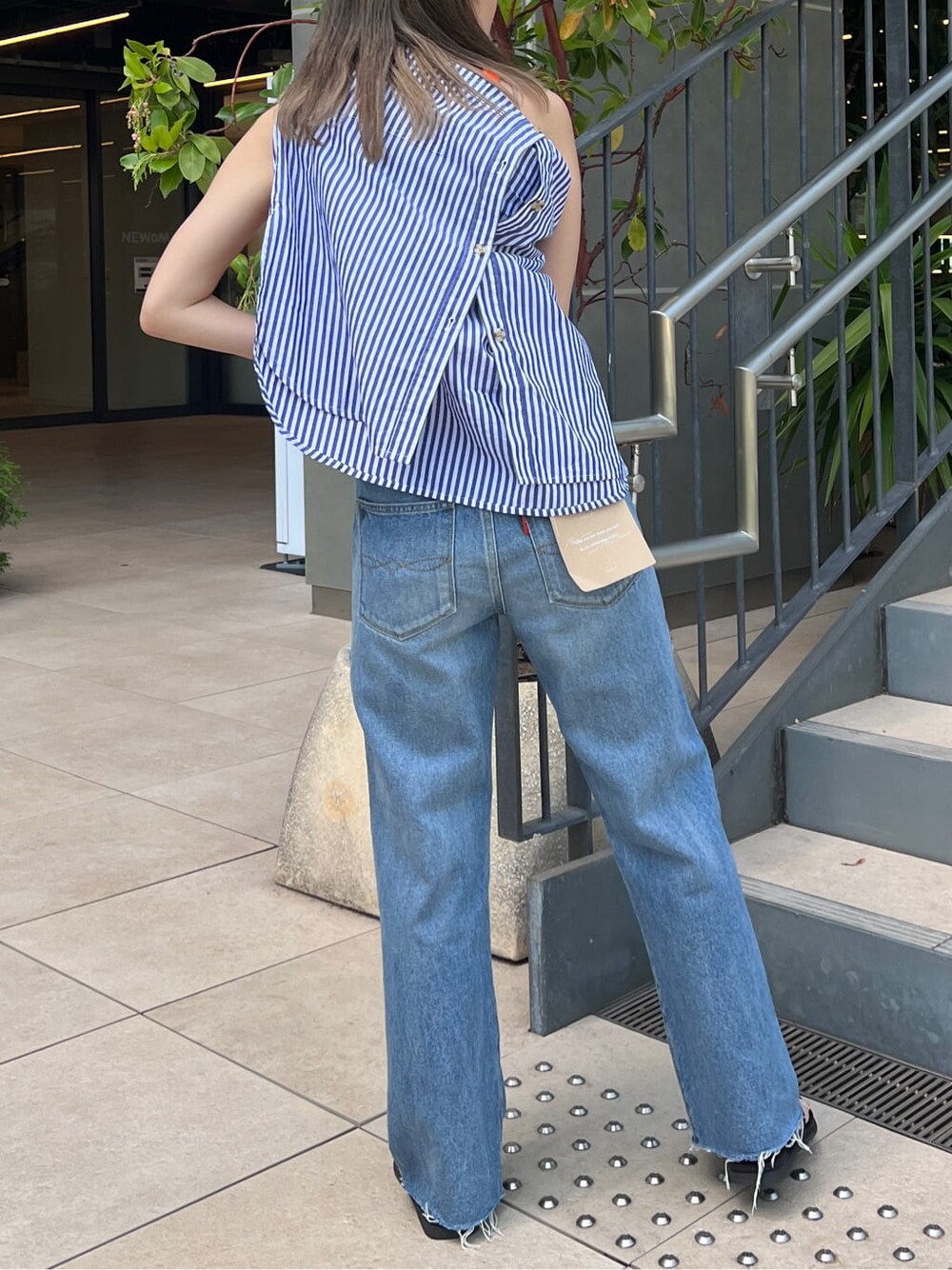 ブルー系のデニムパンツ、オレンジ系のタンクトップ、ブルー系のシャツ/ブラウスを着用したレディースの春コーディネートの2枚目の写真