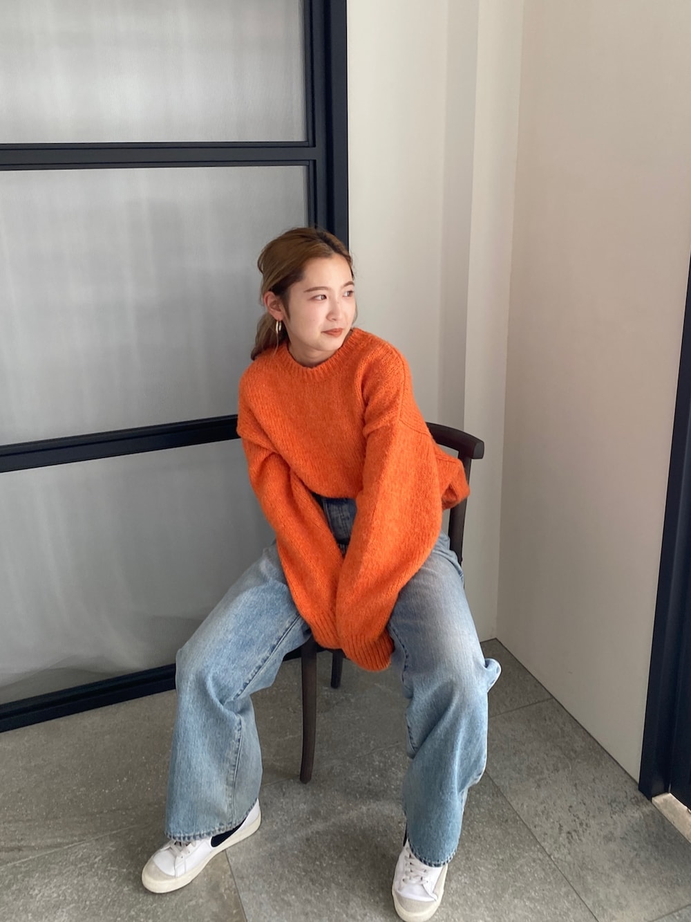 オレンジ系のニット/セーター、ブルー系のデニムパンツを着用したレディースの冬コーディネートの7枚目の写真