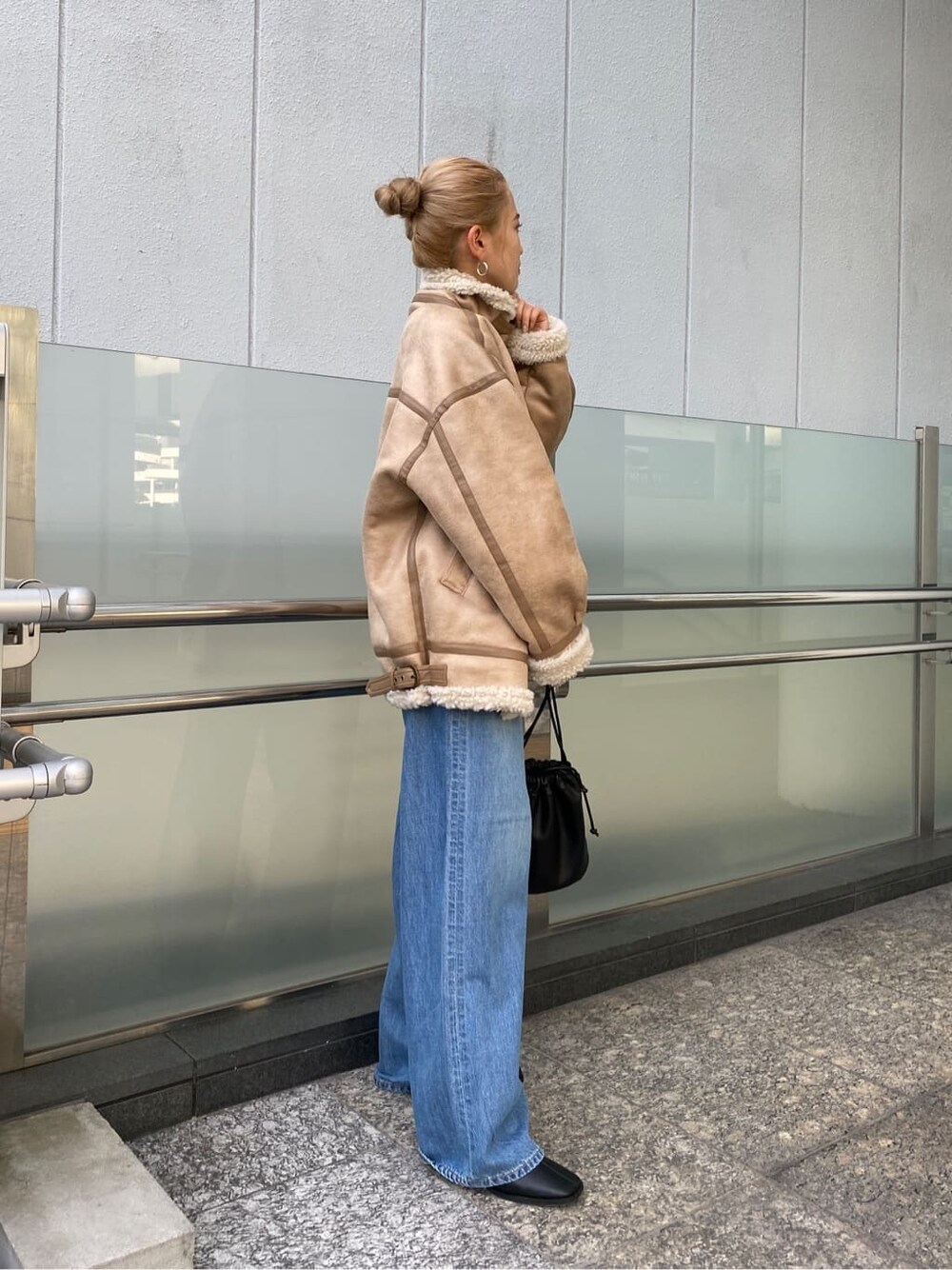 ブルー系のデニムパンツ、ブラック系のブーツ、ブラック系のハンドバッグを着用したレディースの秋コーディネートの4枚目の写真