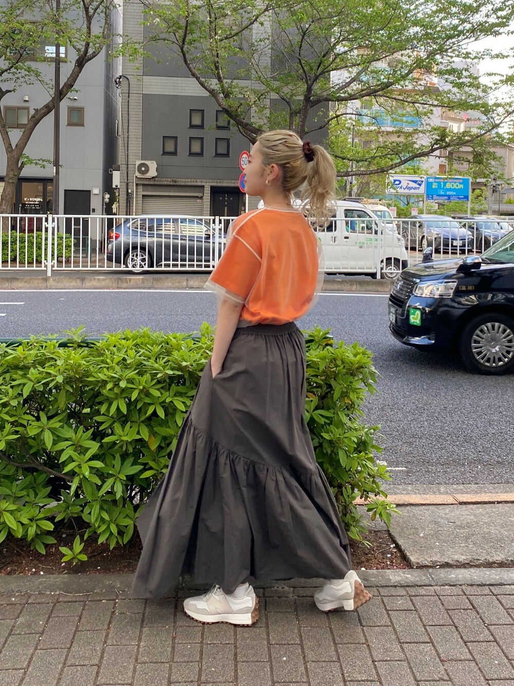 オレンジ系のTシャツ/カットソー、グレー系のスカートを着用したレディースの春コーディネートの4枚目の写真