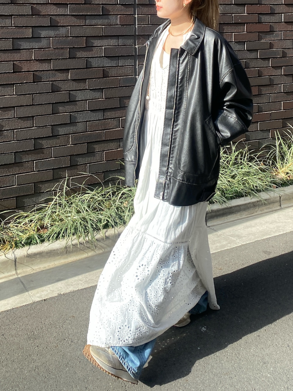 ブラック系のブルゾン、ホワイト系のワンピース、ブルー系のデニムパンツを着用したレディースの冬コーディネートの2枚目の写真