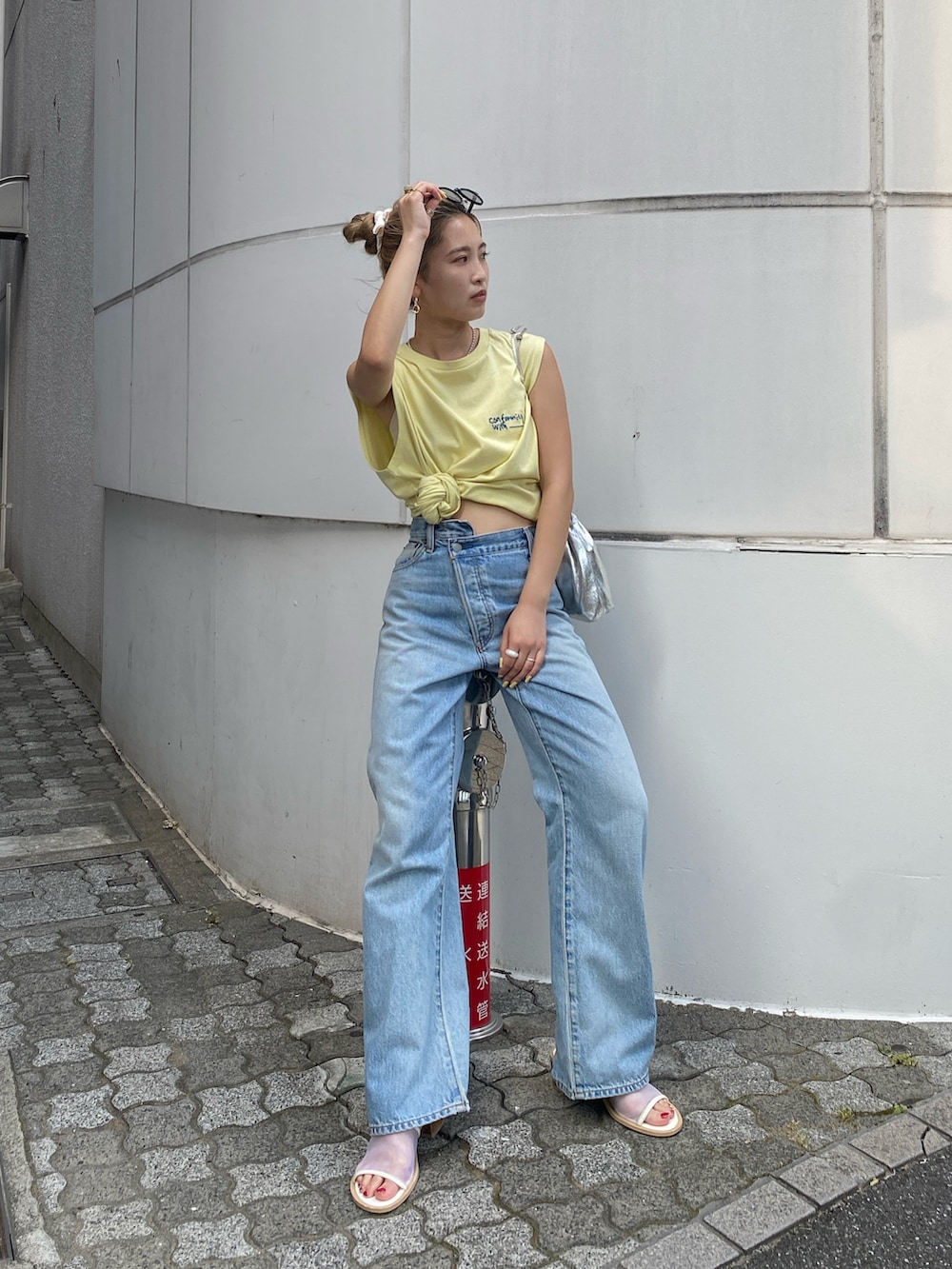 イエロー系のタンクトップ、ブルー系のデニムパンツ、ホワイト系のサンダルを着用したレディースの夏コーディネートの2枚目の写真