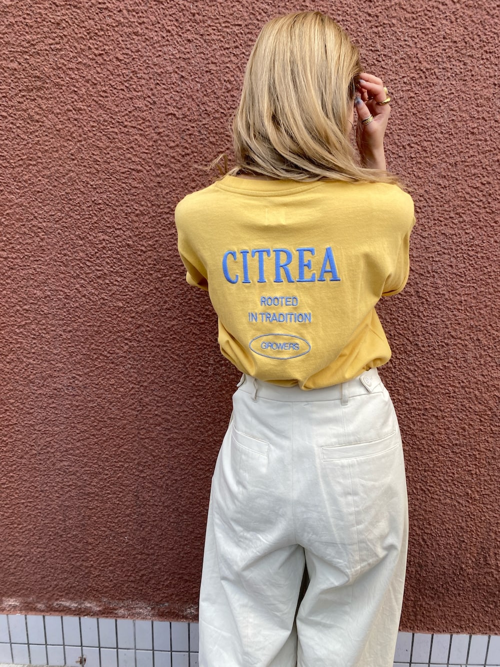 イエロー系のTシャツ/カットソー、ホワイト系のチノパンツを着用したレディースの夏コーディネートの3枚目の写真