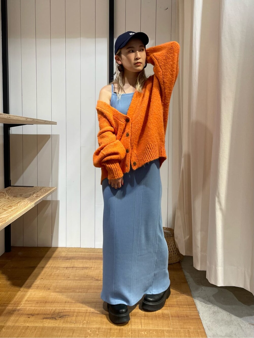 オレンジ系のカーディガン/ボレロ、ブラック系のブーツ、ブルー系のワンピースを着用したレディースの秋コーディネートの3枚目の写真