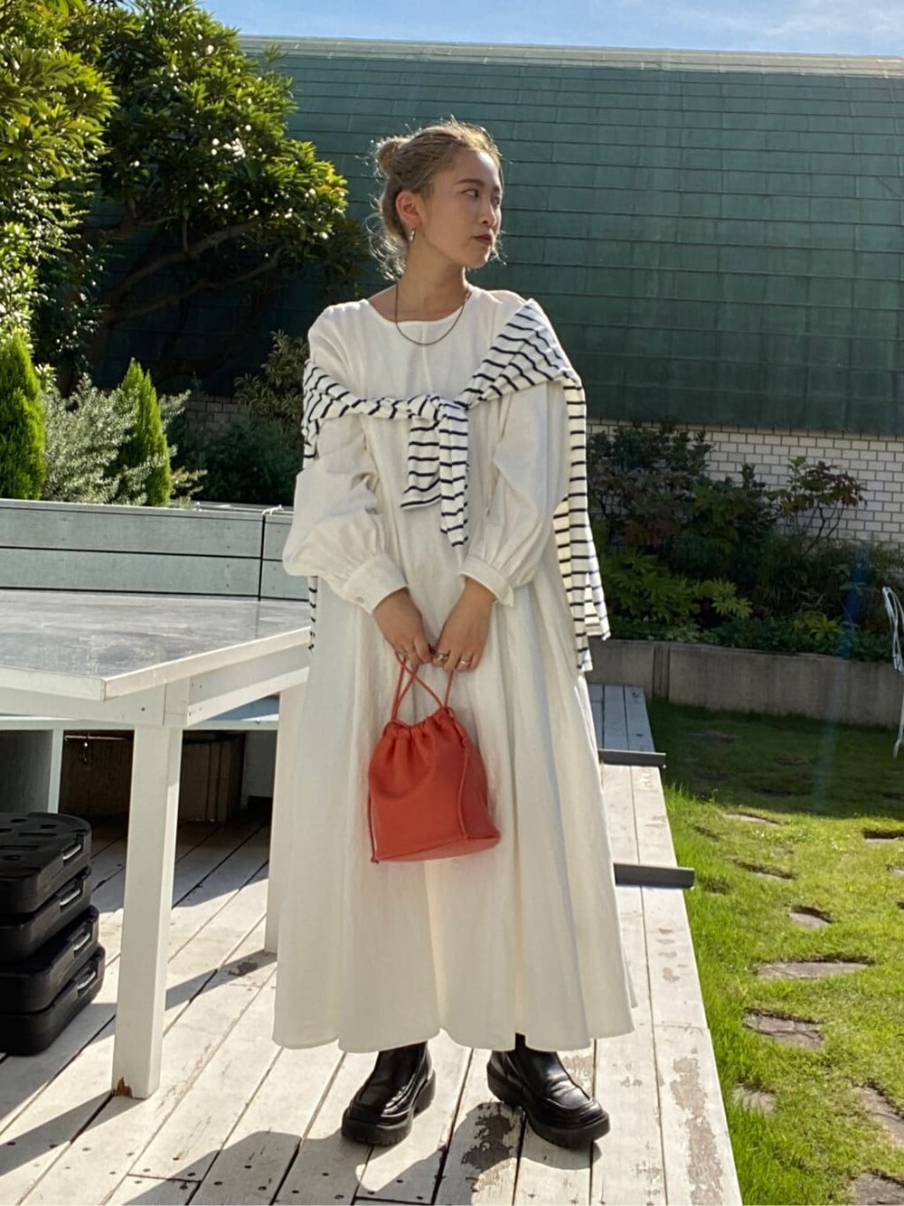 オレンジ系のハンドバッグ、オレンジ系のワンピース、ブルー系のTシャツ/カットソーを着用したレディースの秋コーディネートの2枚目の写真