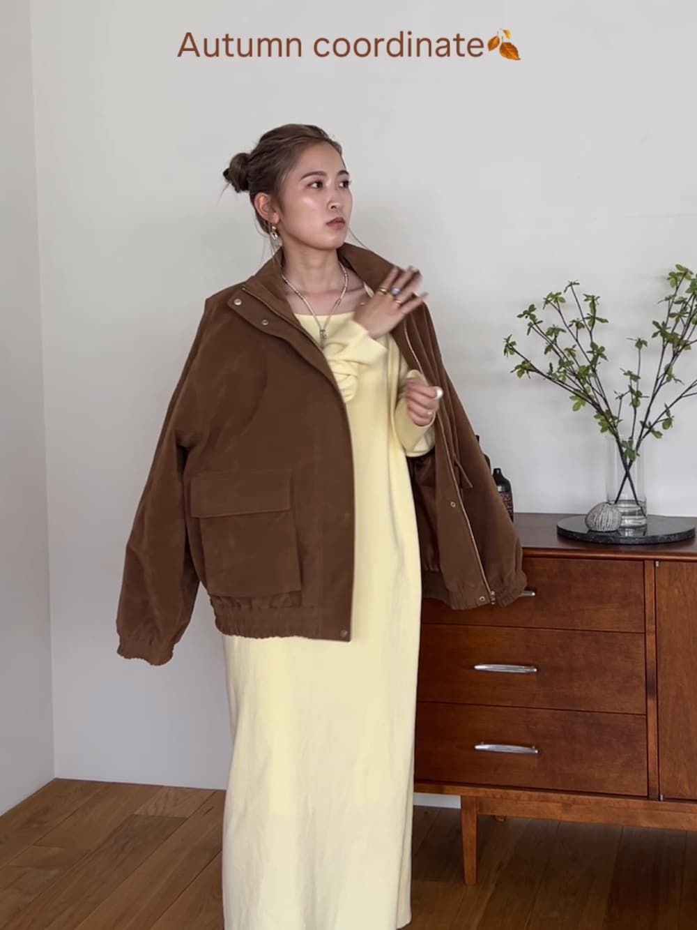 ブラウン系のブルゾン、イエロー系のワンピース、ホワイト系のネックレスを着用したレディースの秋コーディネートの4枚目の写真