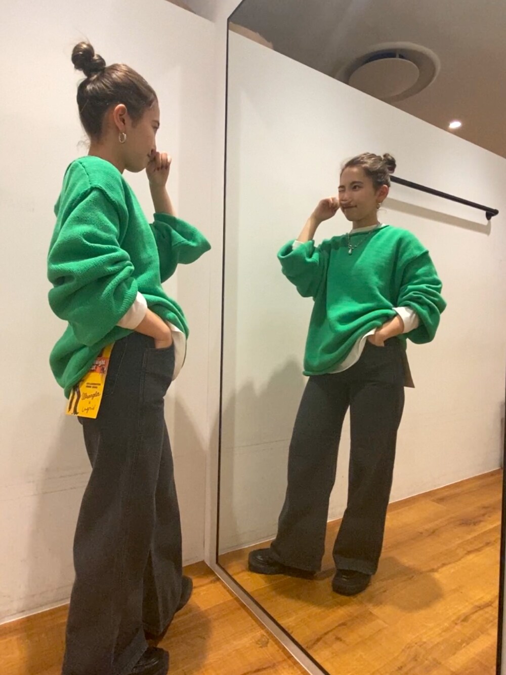 ブラック系のデニムパンツ、ホワイト系のTシャツ/カットソー、グリーン系のニット/セーターを着用したレディースの秋コーディネートの2枚目の写真