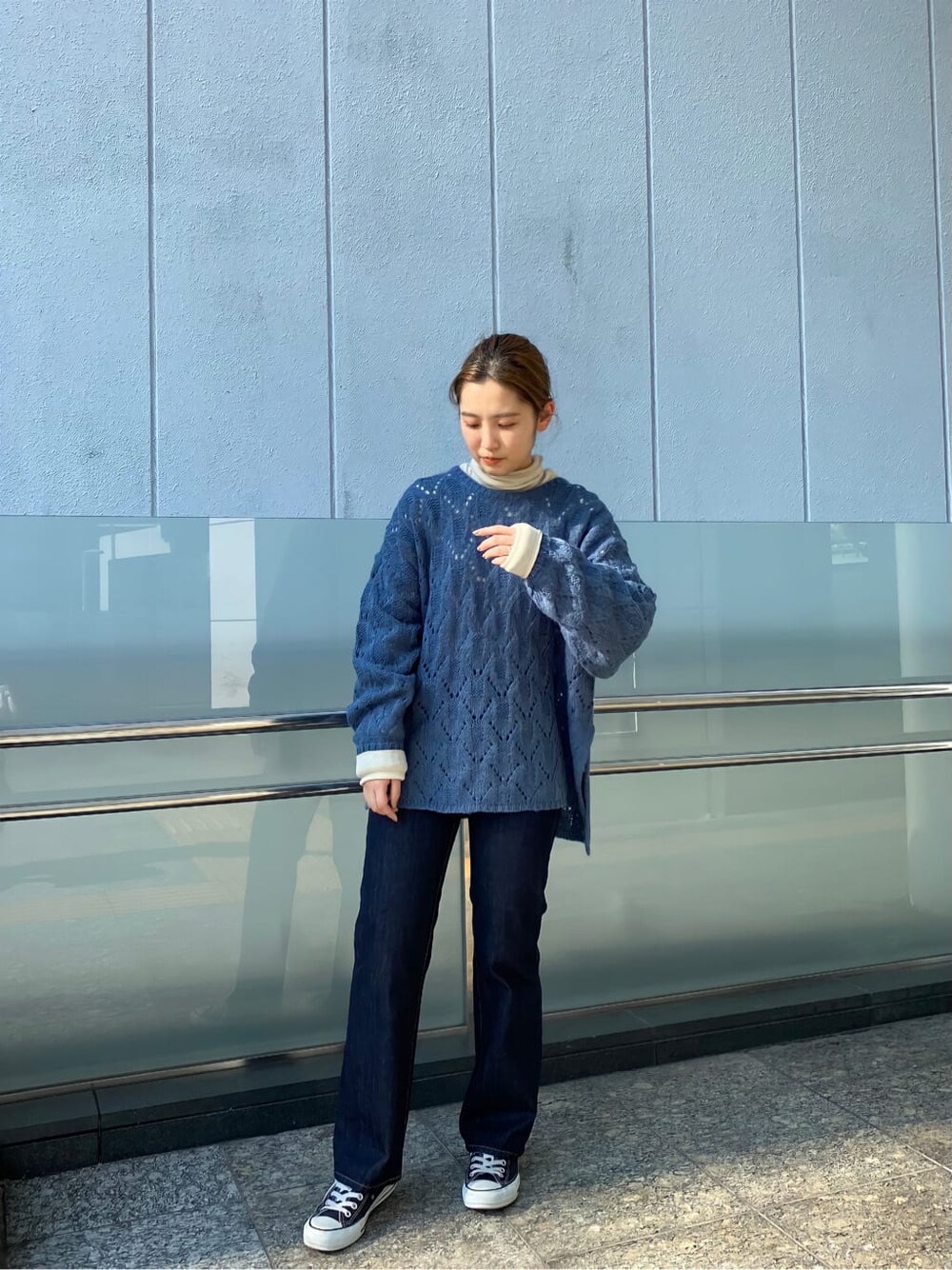 ブルー系のデニムパンツ、ホワイト系のTシャツ/カットソー、ブルー系のニット/セーターを着用したレディースの秋コーディネートの2枚目の写真