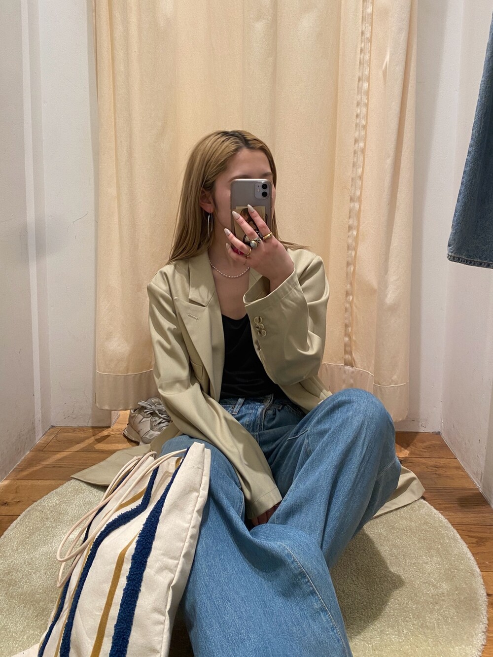 ベージュ系のテーラードジャケット、ブルー系のデニムパンツ、シルバー系のネックレスを着用したレディースの春コーディネートの2枚目の写真